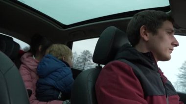 Genç Aile Babası Anne Çocuk Araçla Birlikte Seyahat Ediyor. Country Sahne Arkaplanı Bulutlu Gökyüzü. Sonbahar Kış sezonu. 2x Yavaş çekim 60fps 4K