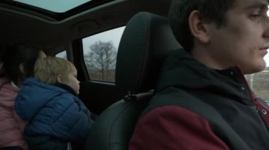 Genç Aile Babası Anne Çocuk Araçla Birlikte Seyahat Ediyor. Country Sahne Arkaplanı Bulutlu Gökyüzü. Sonbahar Kış sezonu. 2x Yavaş çekim 60fps 4K