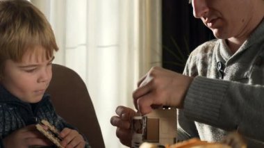 Father with Son Assemble Wooden Toy Truck Constructor. Dad with Child Spend Time Together Handcraft. Winter Holidays Sunny Day Home. 2x Slow motion 60fps 4K