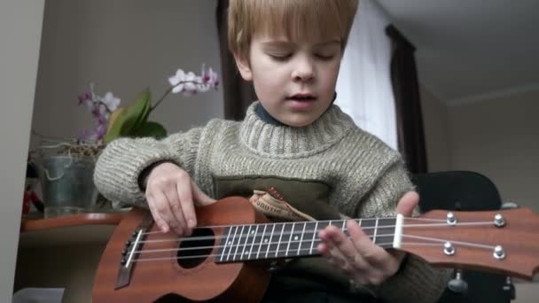 Little Boy Kid Play Ukulele Guitar Home Child Sings Plays — Stockvideo