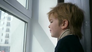 Küçük Çocuk Şehir Hayatı 'nda Pencereden Dışarı Bakıyor. Apartmandaki sevimli çocuk. 2x Yavaş çekim 60fps 4K