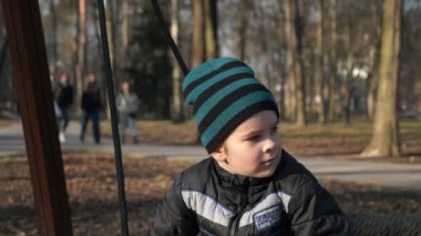 Little Boy Child Swinging on Swing in City Park. Sunny Evening. Slow motion 4K