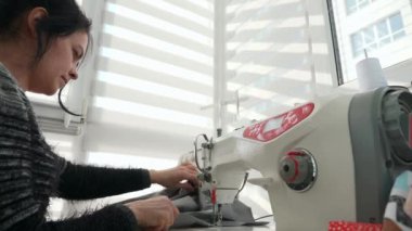 Elektrikli dikiş makinesinde çalışan kadın. Evde Kadın Terzi Çalışması. Güneşli bir gün. 2x Yavaş çekim 60fps 4K