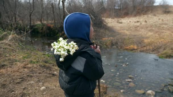 Kind Kid Stands Met Verzamelde Sneeuwdruppel Bloemen Buurt Van River — Stockvideo