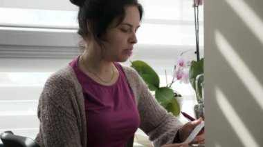 Kontrol Listesi Defteri Yazan Genç Kadın. Dairenin yanındaki Masa Masası 'nda oturan ev hanımı. 2x Yavaş çekim 60fps 4K