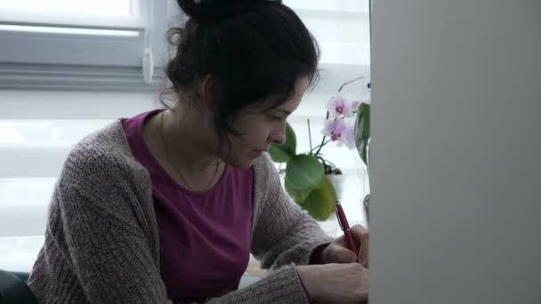 Młoda Kobieta Pisze List Kontrolny Gospodyni Domowa Siedzi Przy Stole — Wideo stockowe