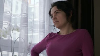 Ciddi Kadın Çiçeklerle Pencereye Bakmayı Düşünüyor. Düşünceli İfade Duyguları. Bayan Ev Kadını Evde Rahatlayın. 2x Yavaş çekim 60fps 4K