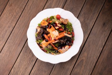 Sebzeli salata tabağı ve ahşap masa manzaralı ızgara somon.