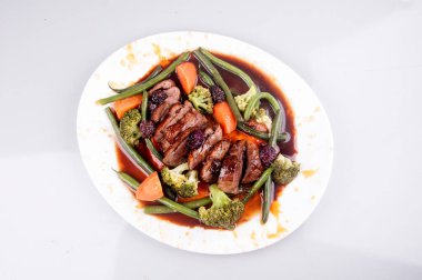 Beyaz tabakta sebzeli ördek magreti.