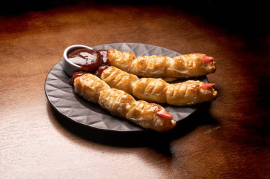 Cadılar bayramı sosisi. Cadı parmağına sarılmış. Hamur işi barbekü sosu, dökülen kan gibi.