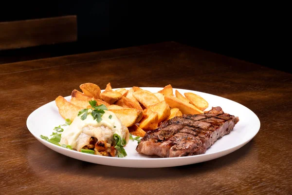 surf and turf - fried fish dish with grilled steak and potatoes front view on wooden table