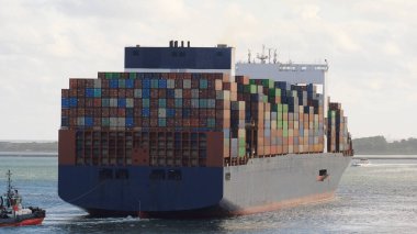 Rotterdam, Hollanda - 10 19 2021: Çok büyük bir konteyner gemisi limandan kıç tarafından römorkör yardımıyla ayrılıyor