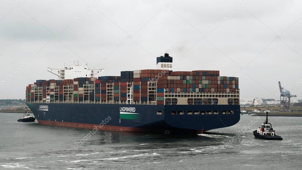 Rotterdam, Netherlands - 07 19 2021: Very large container vessel leaving the port with tug assistance from the stern and from the bow