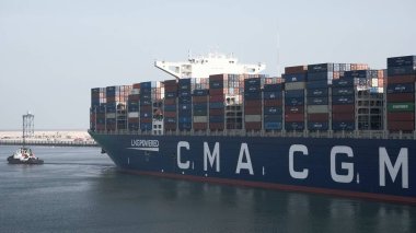 Port of Rotterdam, the Netherlands - 21-09-2021: Huge LNG-powered container ship leaving the port with the assistance of the tug