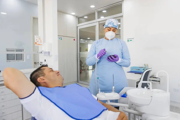 病院の男性に対する歯科処置のための医療ツールの準備と一致している女性の胃科医 — ストック写真