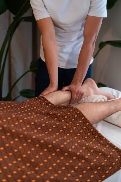 Nierozpoznawalny Terapeuta Masujący Nogi Męskiego Klienta Podczas Masażu Tajskiego Centrum — Zdjęcie stockowe