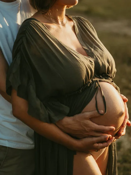 田舎の牧草地に立っている間に後ろからの認識できない男性の巨大な妊娠中の女性 — ストック写真