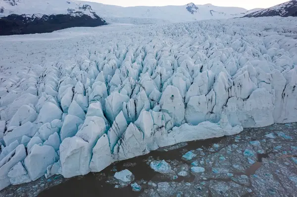 冬のアイスランドの荒い氷河の近くの冷たい海の水に浮かぶ氷の流れのドローンの上から — ストック写真