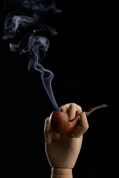 スタジオで黒を背景に木製の手で煙と伝統的なタバコパイプ — ストック写真
