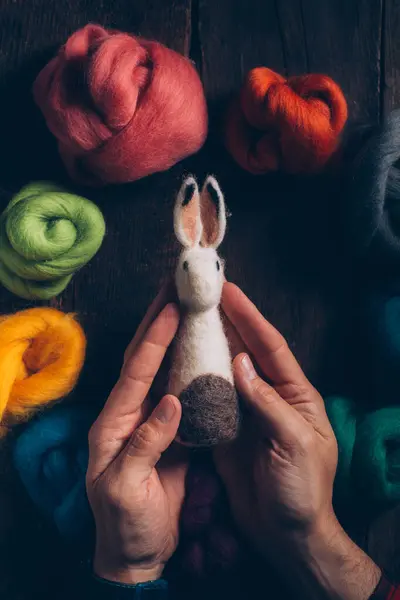 手牵着一只手 用羊毛做的东亚兔子 用深色木桌触摸着 — 图库照片