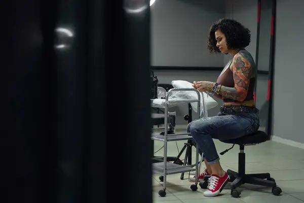 Poważna Dorosła Kobieta Luźnych Ubraniach Tatuażami Siedząca Jasnym Salonie Tatuażu — Zdjęcie stockowe
