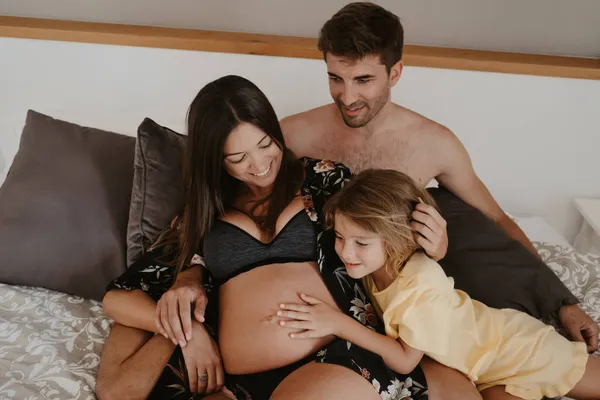 Criança Acariciando Barriga Mãe Grávida Sorridente Lingerie Deitada Cama Com — Fotografia de Stock