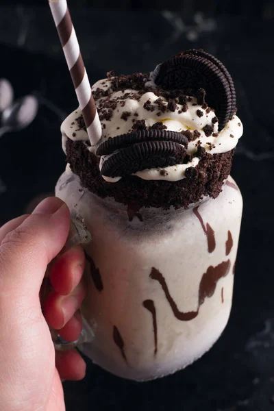 ホイップクリームとチョコレートクッキーとおいしいシェイクで匿名の人をジャーの上にクロップ — ストック写真