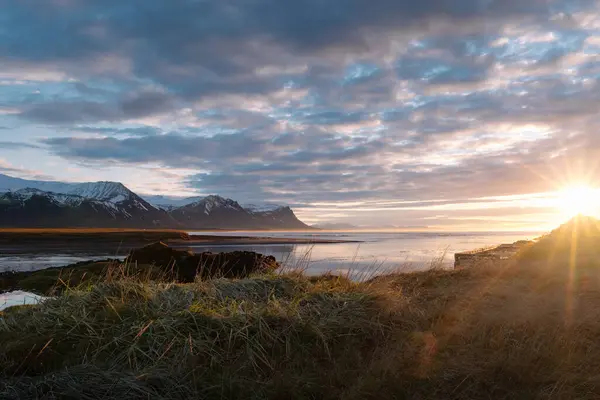 アイスランドの美しい日没の空の下で雪の山に囲まれた穏やかな湖の息をのむような風景 — ストック写真