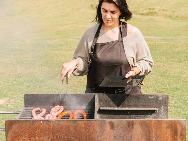 Chef Feminino Concentrado Com Pinças Avental Cozinhando Salsichas Grelha Grelhar — Fotografia de Stock