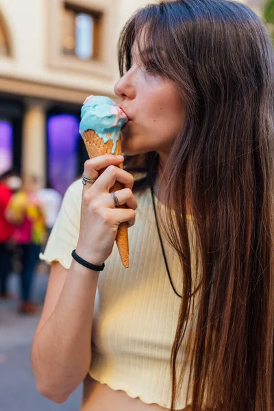 クロップ若いです女性なめるおいしいジェラートでワッフルコーンで町のぼやけた背景 — ストック写真