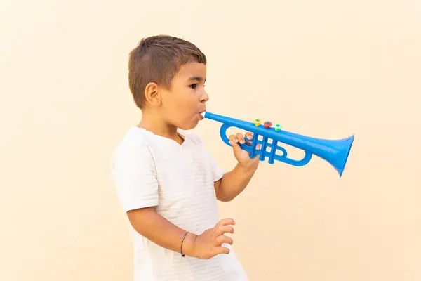 Vista Lateral Menino Bonito Tocando Trompete Brinquedo Azul Perto Parede — Fotografia de Stock