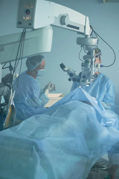 Médico Anônimo Uniforme Estéril Olhando Através Microscópio Sobre Paciente Cama — Fotografia de Stock