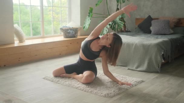 En ung kvinna är engagerad i gymnastik och yoga hemma. — Stockvideo