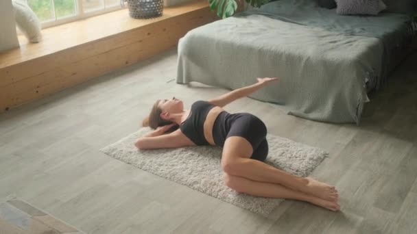 Una mujer joven se dedica a la gimnasia y el yoga en casa. — Vídeos de Stock