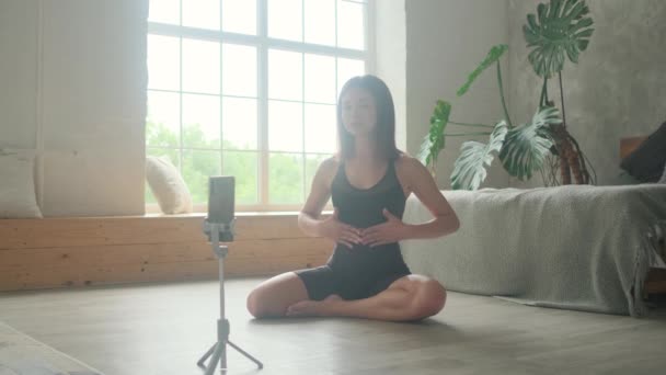 Een sport meisje blogger leert hoe om correct te ademen online via de telefoon. — Stockvideo