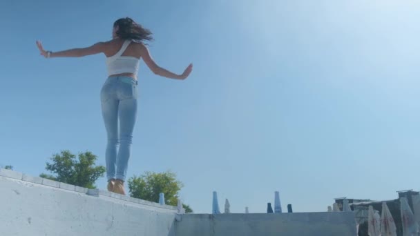 在一个阳光明媚的夏日，一个穿牛仔裤的女孩正在街上跳八方块舞. — 图库视频影像