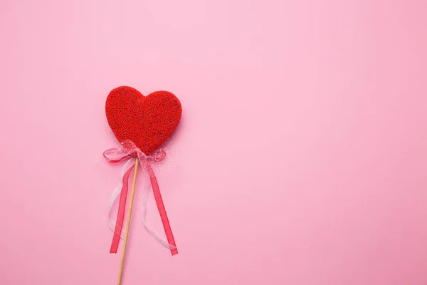 Fechar-se de um coração com um cenário em um pau em um contexto isolado rosa. Feitiço amor em letras brancas. — Fotografia de Stock