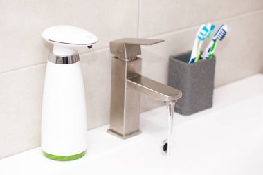 Banyoda otomatik sıvı sabun dağıtıcısı var..