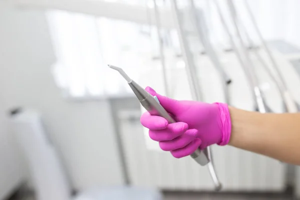 Mão feminina com luvas cor-de-rosa no consultório dentário. Mantém uma ferramenta de close-up — Fotografia de Stock
