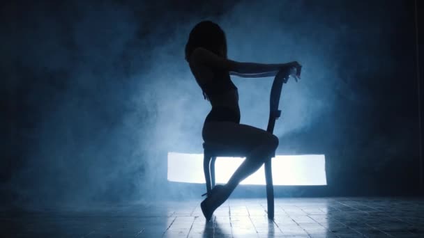 Silhouette d'une fille sexy dansant une danse sensuelle érotique en fumée bleue. — Video