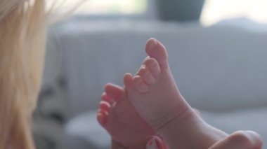 Genç anne, emziren küçük bir çocuğun bacağını öpüyor..