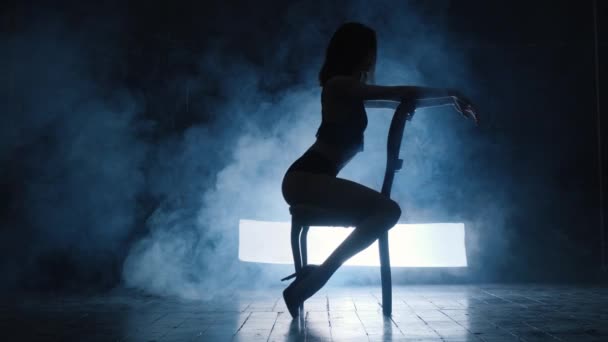 Silhouette d'une fille sexy dansant une danse sensuelle érotique en fumée bleue. — Video