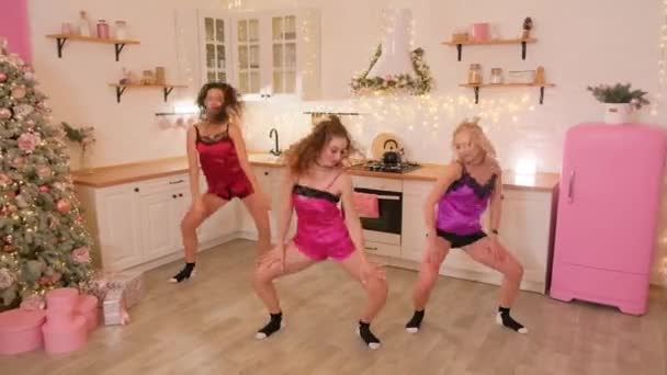 Tre tjejer i pyjamas dansar vackert synkront i köket. — Stockvideo