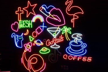 Siyah bir duvarda çeşitli neon şekiller vardı. Parlayan çok renkli neon.