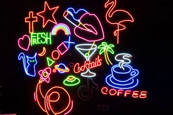 Siyah bir duvarda çeşitli neon şekiller vardı. Parlayan çok renkli neon.