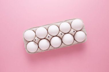 Pembe arka planda yakın plan bir tepside tavuk yumurtası.