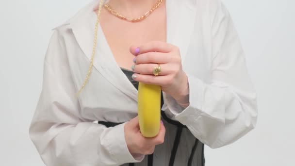 Girl holding a banana in her hands on a white background, playing masturbation and imitation of a mans penis. — Vídeo de stock