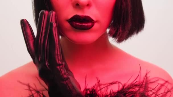 Lèvres avec rouge à lèvres noir brillant gros plan. Portrait de beauté d'une fille sur fond blanc au teint rouge. — Video