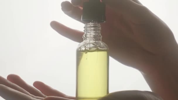 Kosmetiköl auf einer weiblichen Hand in Nahaufnahme auf weißem Hintergrund. — Stockvideo