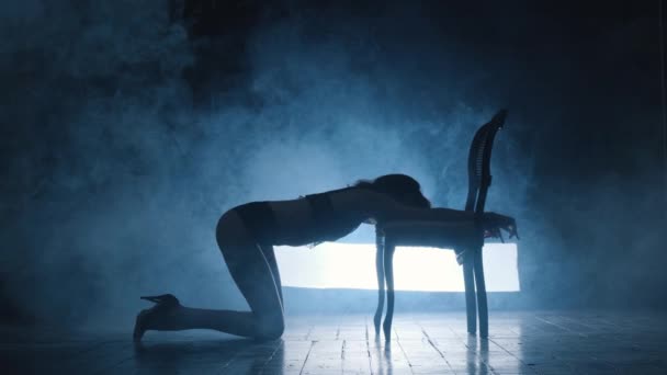 Silhouette d'une fille sexy dansant une danse sensuelle érotique en fumée bleue. — Video